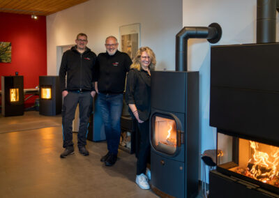 Team Geschäftsführung & Vertrieb in Showroom 1 vor brennenden Kaminöfen